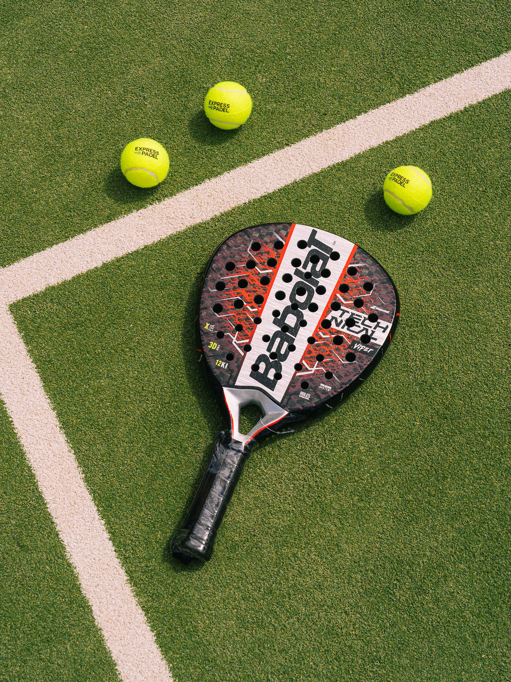 Babolat Technical Viper Paddle and tennis balls on a green court with a visible brand logo.